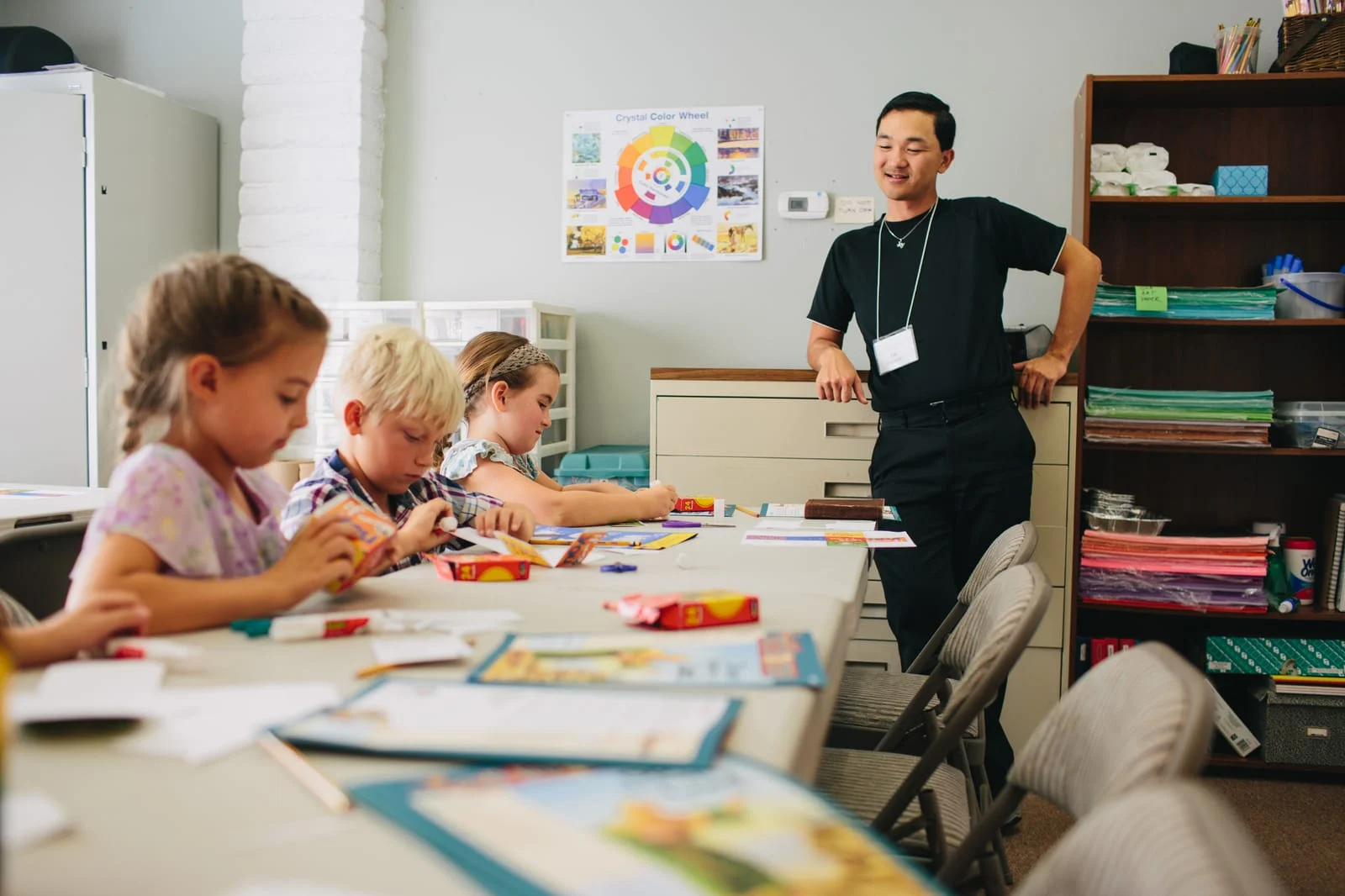 A teacher with children at a craft table in a Sunday school classroom