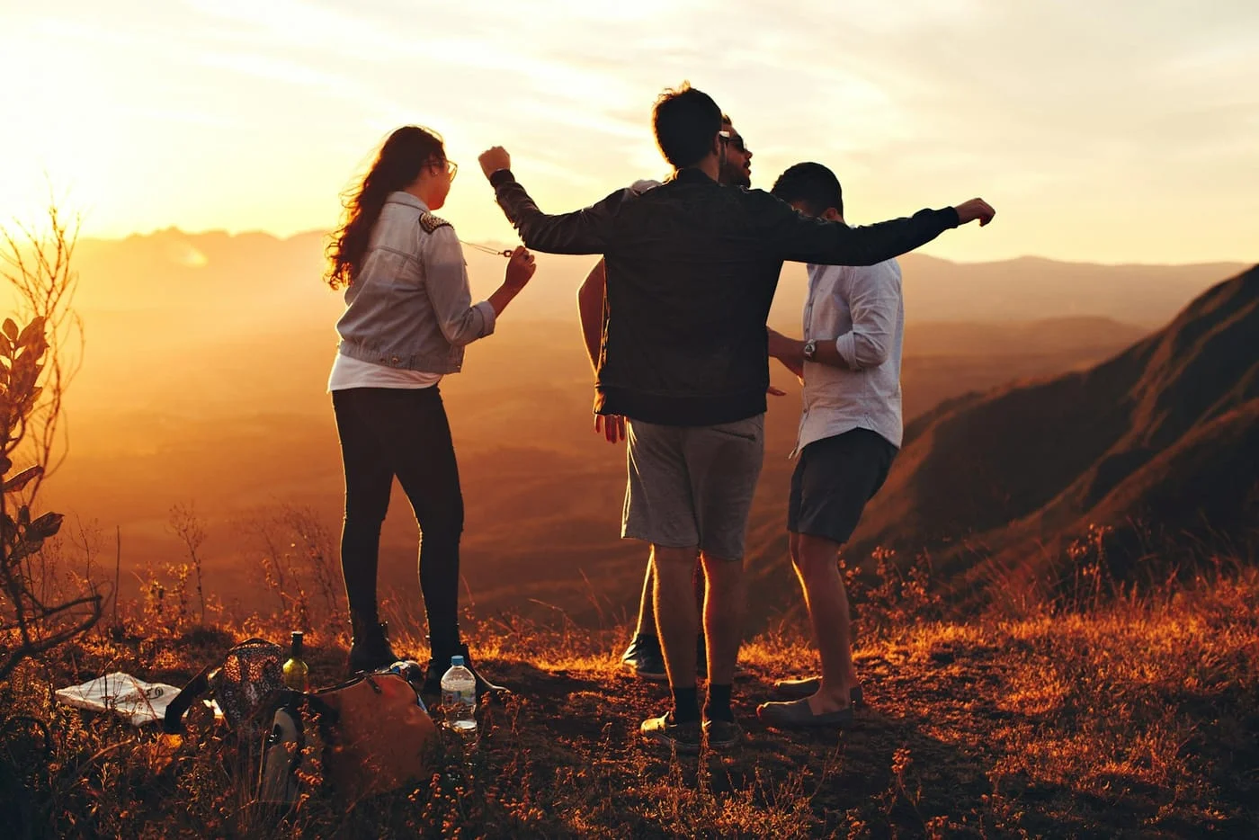 Friends standing together on a hillside at sunset
